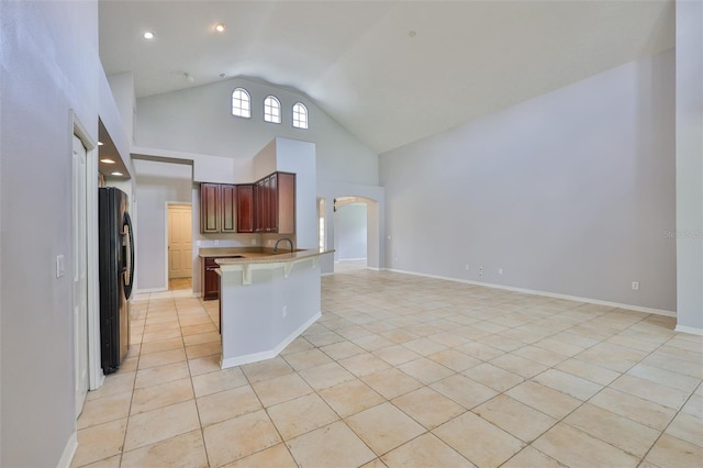 7114 Cromwell Park Ln, Apollo Beach, FL 33572 - kitchen featuring light tile patterned flooring, black fridge, a peninsula, light countertops, and high vaulted ceiling