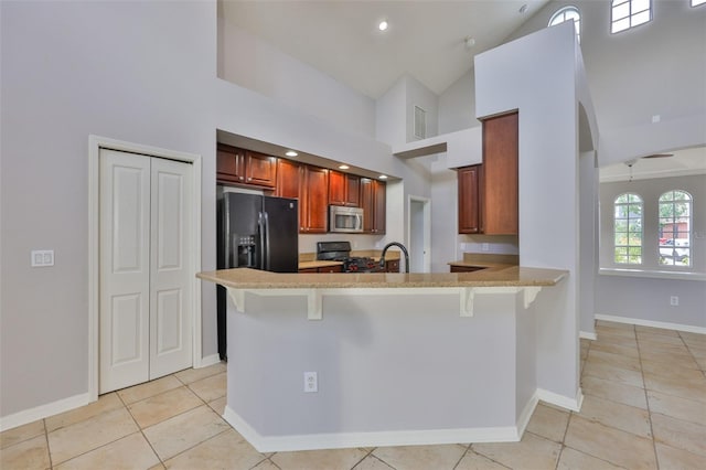 7114 Cromwell Park Ln, Apollo Beach, FL 33572 - kitchen with black appliances, high vaulted ceiling, a kitchen bar, light tile patterned floors, and a peninsula