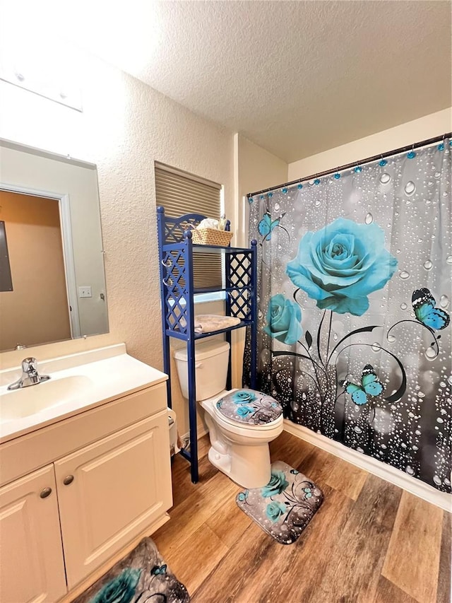 5351 Leisure Ln, New Port Richey, FL 34652 - full bathroom featuring a textured wall, wood finished floors, a textured ceiling, toilet, and vanity
