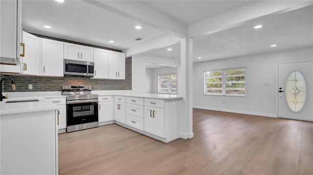 603 Amana Ave, Brandon, FL 33510 - kitchen featuring stainless steel appliances, a sink, light wood-style flooring, light countertops, and beamed ceiling