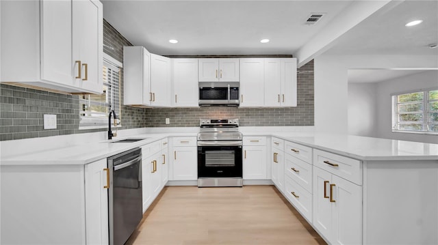 603 Amana Ave, Brandon, FL 33510 - kitchen with appliances with stainless steel finishes, a sink, a peninsula, white cabinets, and tasteful backsplash