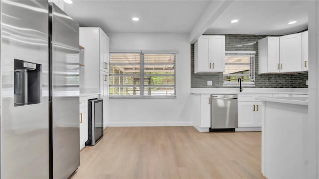 603 Amana Ave, Brandon, FL 33510 - kitchen featuring appliances with stainless steel finishes, wine cooler, light countertops, light wood-type flooring, and baseboards