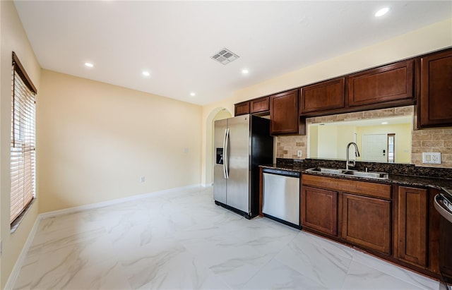 3305 Hoylake Ct, Land O Lakes, FL 34638 - kitchen featuring appliances with stainless steel finishes, backsplash, light marble finish flooring, dark stone countertops, and arched walkways