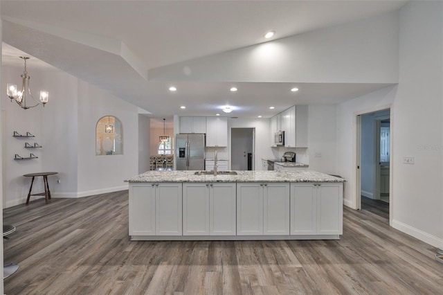 1034 Brighton Way, Lakeland, FL 33813 - kitchen featuring appliances with stainless steel finishes, a sink, wood finished floors, white cabinetry, and vaulted ceiling