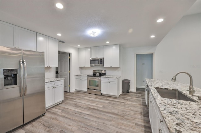 1034 Brighton Way, Lakeland, FL 33813 - kitchen featuring appliances with stainless steel finishes, a sink, light wood-type flooring, white cabinetry, and light stone countertops