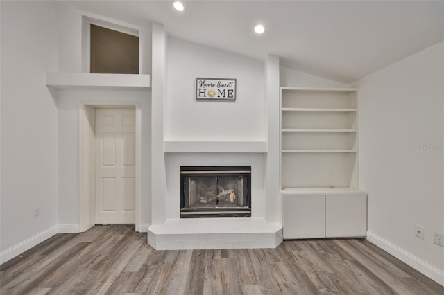 1034 Brighton Way, Lakeland, FL 33813 - unfurnished living room featuring lofted ceiling, a fireplace with raised hearth, wood finished floors, baseboards, and recessed lighting