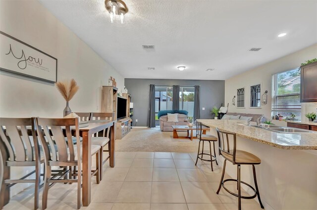3320 Pleasant Willow Ct, Brandon, FL 33511 - kitchen featuring a sink, a breakfast bar, light carpet, light stone countertops, and open floor plan