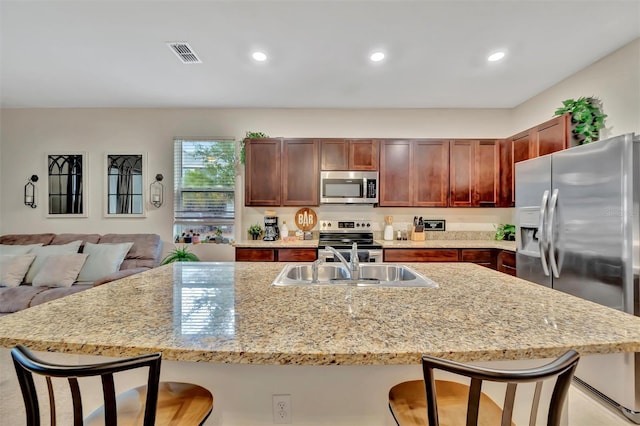 3320 Pleasant Willow Ct, Brandon, FL 33511 - kitchen featuring stainless steel appliances, a sink, a breakfast bar area, light stone countertops, and recessed lighting