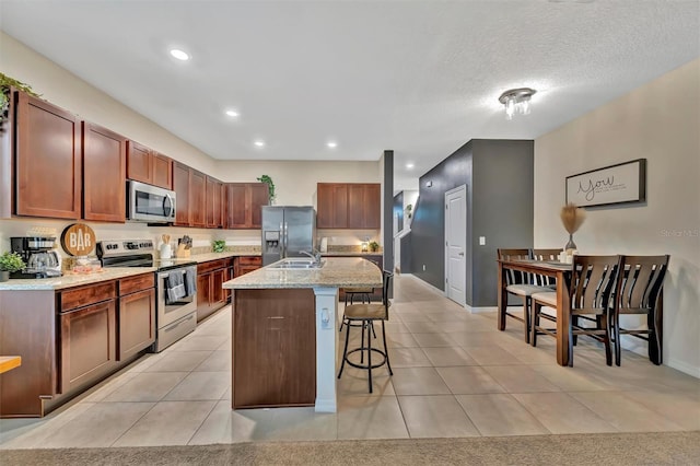 3320 Pleasant Willow Ct, Brandon, FL 33511 - kitchen featuring stainless steel appliances, a kitchen breakfast bar, light tile patterned floors, an island with sink, and light stone counters