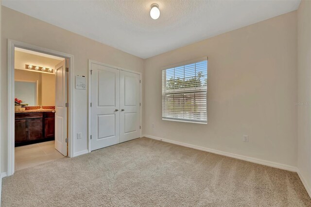3320 Pleasant Willow Ct, Brandon, FL 33511 - unfurnished bedroom featuring light colored carpet, baseboards, ensuite bathroom, a closet, and a textured ceiling