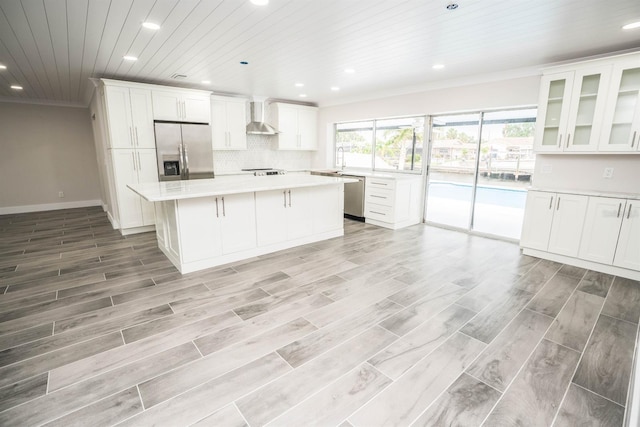 913 Spindle Palm Way, Apollo Beach, FL 33572 - kitchen with appliances with stainless steel finishes, wall chimney range hood, crown molding, a center island, and recessed lighting