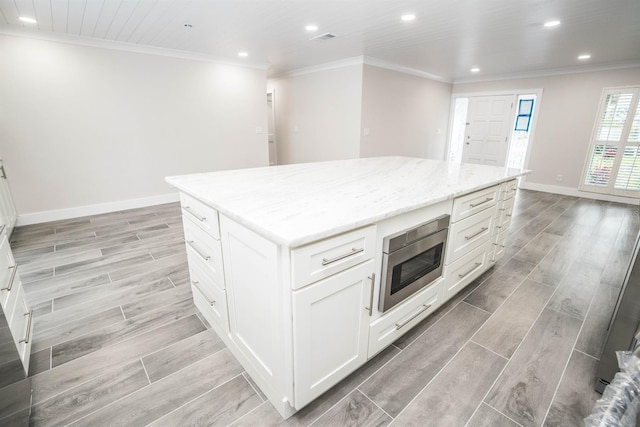 913 Spindle Palm Way, Apollo Beach, FL 33572 - kitchen with stainless steel microwave, wood finish floors, recessed lighting, a center island, and crown molding