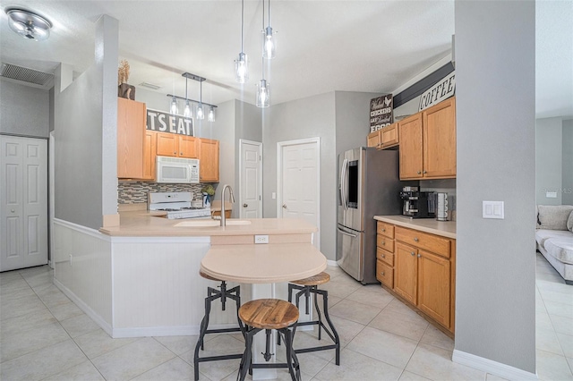 1135 Millbrook Cir, Bradenton, FL 34212 - kitchen featuring white appliances, a peninsula, tasteful backsplash, light tile patterned floors, and light countertops