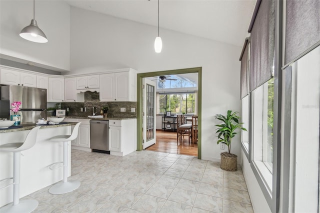 18914 Geraci Rd, Lutz, FL 33548 - kitchen featuring stainless steel appliances, high vaulted ceiling, decorative backsplash, white cabinetry, and pendant lighting