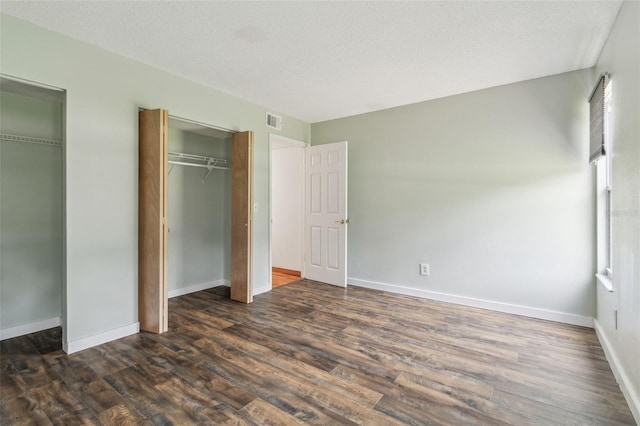 18914 Geraci Rd, Lutz, FL 33548 - unfurnished bedroom featuring dark wood-type flooring, multiple closets, and a textured ceiling