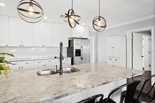 3906 W Rogers Ave, Tampa, FL 33611 - kitchen featuring stainless steel fridge with ice dispenser, a breakfast bar area, white cabinets, light stone countertops, and crown molding
