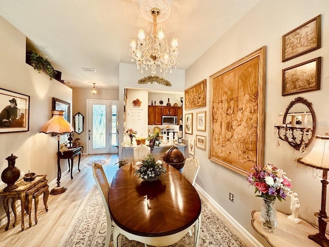 5103 98th Ave E, Parrish, FL 34219 - dining room with light wood-style flooring, a chandelier, and baseboards