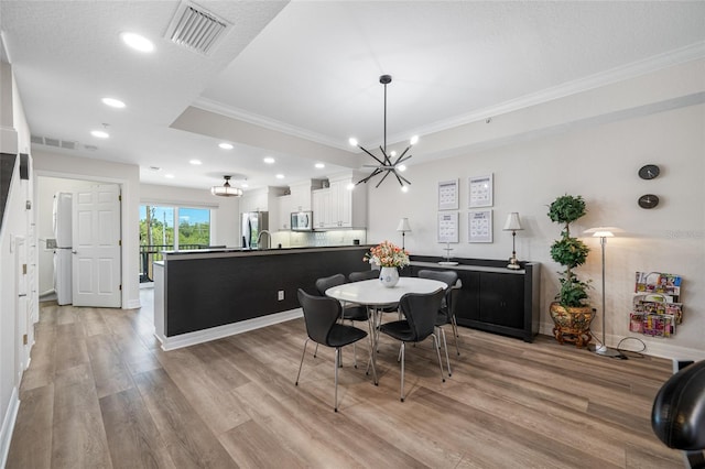 340 1st St N Unit I, Saint Petersburg, FL 33701 - dining area featuring crown molding, light wood-style flooring, recessed lighting, a chandelier, and a raised ceiling