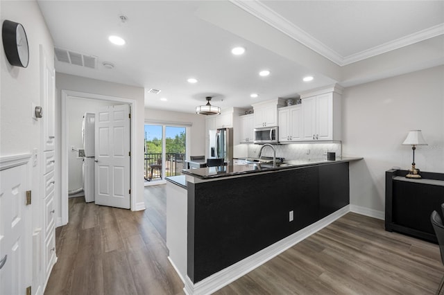 340 1st St N Unit I, Saint Petersburg, FL 33701 - kitchen with appliances with stainless steel finishes, ornamental molding, a peninsula, recessed lighting, and dark wood-type flooring