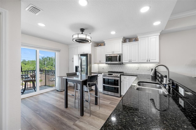 340 1st St N Unit I, Saint Petersburg, FL 33701 - kitchen with appliances with stainless steel finishes, a sink, tasteful backsplash, white cabinetry, and dark stone counters