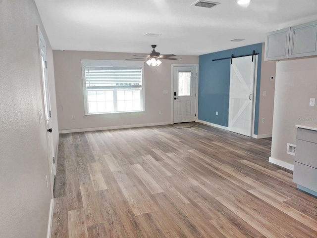 5969 NW 65th St, Ocala, FL 34482 - unfurnished living room with a barn door, light wood-style floors, a ceiling fan, and baseboards