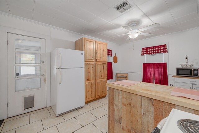 1235 Bass Blvd, Dunedin, FL 34698 - kitchen featuring freestanding refrigerator, stainless steel microwave, ceiling fan, light tile patterned flooring, and ornamental molding