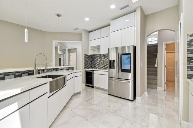 1460 Kensington Woods Dr, Lutz, FL 33549 - kitchen with stainless steel refrigerator with ice dispenser, wine cooler, light countertops, white cabinets, and recessed lighting