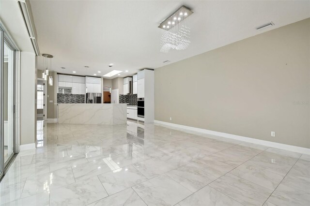 1460 Kensington Woods Dr, Lutz, FL 33549 - unfurnished living room with light marble finish floors, a chandelier, and recessed lighting