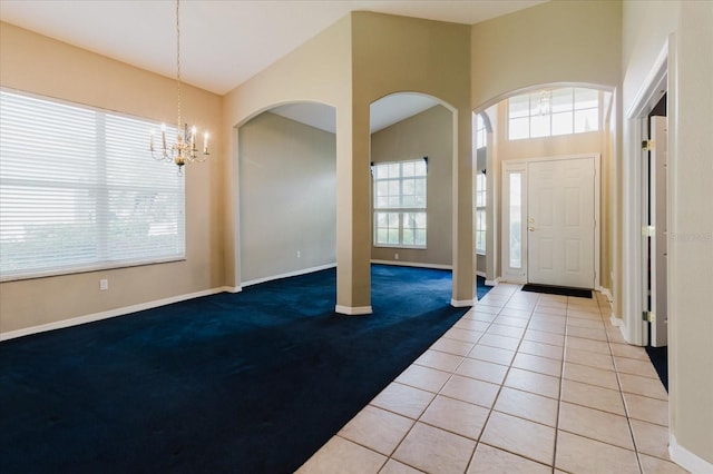 1852 Longview Ln, Tarpon Springs, FL 34689 - carpeted foyer entrance featuring a chandelier, baseboards, arched walkways, and tile patterned flooring