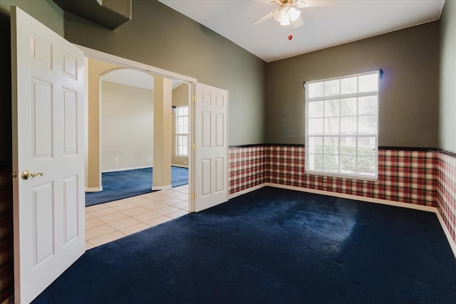 1852 Longview Ln, Tarpon Springs, FL 34689 - tiled spare room featuring carpet flooring, a ceiling fan, wallpapered walls, wainscoting, and arched walkways