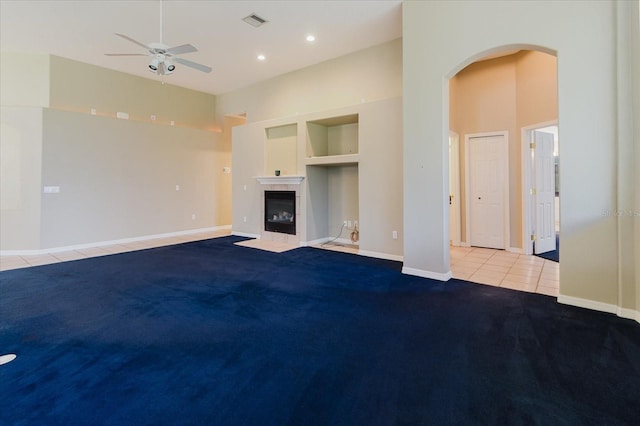1852 Longview Ln, Tarpon Springs, FL 34689 - unfurnished living room with a ceiling fan, a tiled fireplace, arched walkways, carpet floors, and tile patterned floors