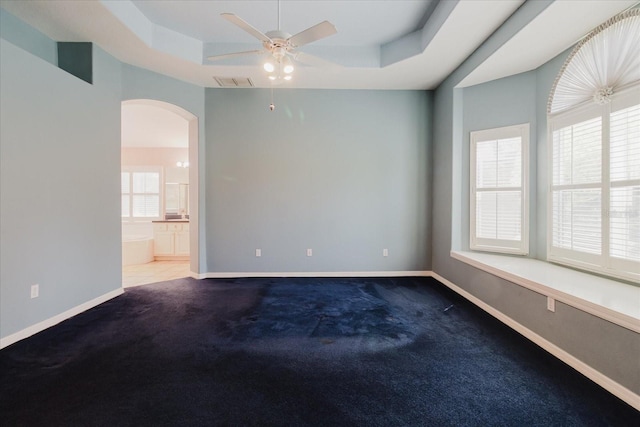 1852 Longview Ln, Tarpon Springs, FL 34689 - unfurnished room featuring arched walkways, a raised ceiling, ceiling fan, baseboards, and carpet