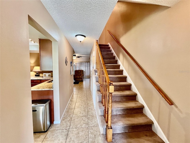 2131 Ridge Rd S Unit 76, Largo, FL 33778 - stairs featuring a textured ceiling, tile patterned flooring, ceiling fan, and baseboards