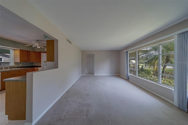 501 Poinsettia Rd, Belleair, FL 33756 - unfurnished living room featuring baseboards, ceiling fan, light carpet, and a sink