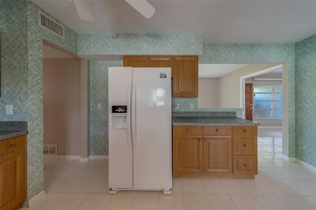 501 Poinsettia Rd, Belleair, FL 33756 - kitchen featuring white refrigerator with ice dispenser, baseboards, light tile patterned flooring, brown cabinetry, and ceiling fan