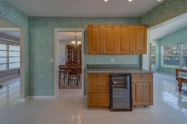501 Poinsettia Rd, Belleair, FL 33756 - kitchen with wine cooler, a chandelier, baseboards, light tile patterned flooring, and brown cabinetry