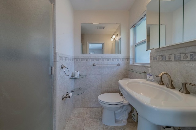 501 Poinsettia Rd, Belleair, FL 33756 - full bathroom with tile walls, toilet, a shower stall, tile patterned flooring, and a sink