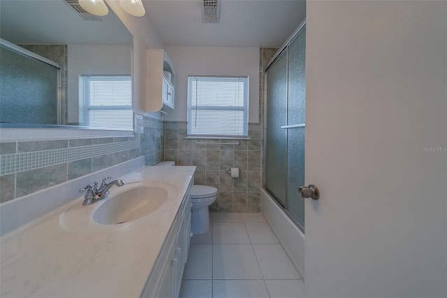 501 Poinsettia Rd, Belleair, FL 33756 - bathroom with tile walls, tile patterned flooring, toilet, vanity, and combined bath / shower with glass door