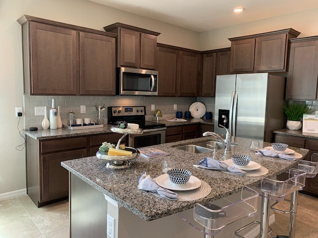 4444 Aqua Mirage St, Sarasota, FL 34238 - kitchen featuring stainless steel appliances, stone counters, decorative backsplash, a center island with sink, and dark brown cabinets
