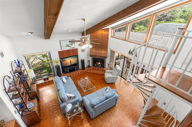 3133 Harvest Moon Dr, Palm Harbor, FL 34683 - living room featuring a lit fireplace, a ceiling fan, beam ceiling, stairs, and wood finished floors