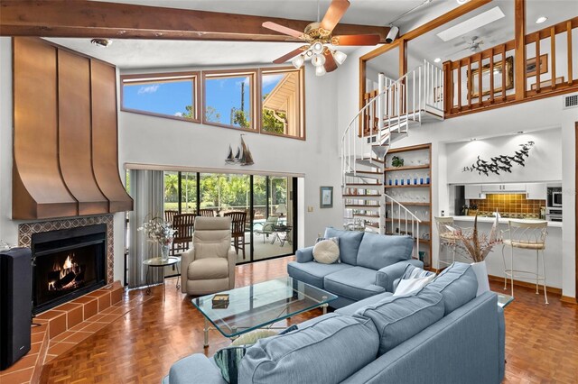 3133 Harvest Moon Dr, Palm Harbor, FL 34683 - living room featuring ceiling fan, a tile fireplace, a towering ceiling, beam ceiling, and stairs
