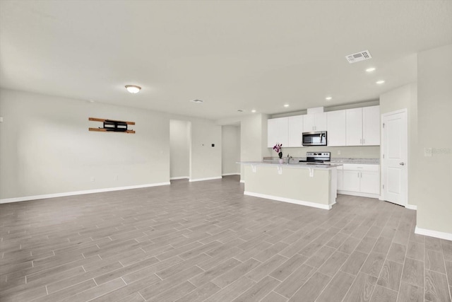 3146 Forrest Plum Ct, Zephyrhills, FL 33540 - kitchen with stainless steel appliances, open floor plan, light wood-style flooring, baseboards, and recessed lighting