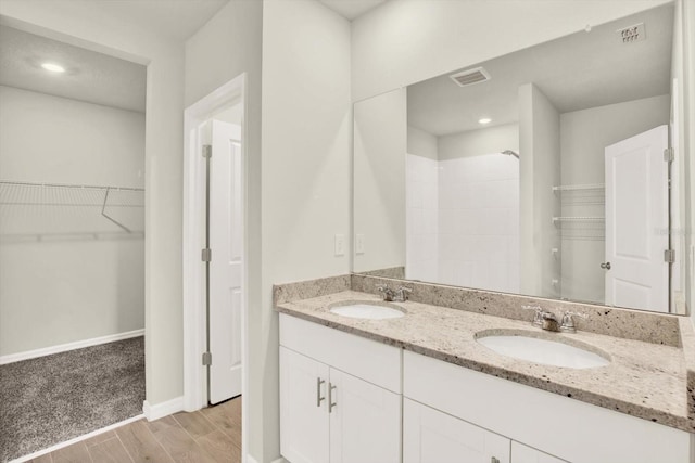 3146 Forrest Plum Ct, Zephyrhills, FL 33540 - bathroom featuring double vanity, wood finished floors, a walk in closet, a shower, and baseboards