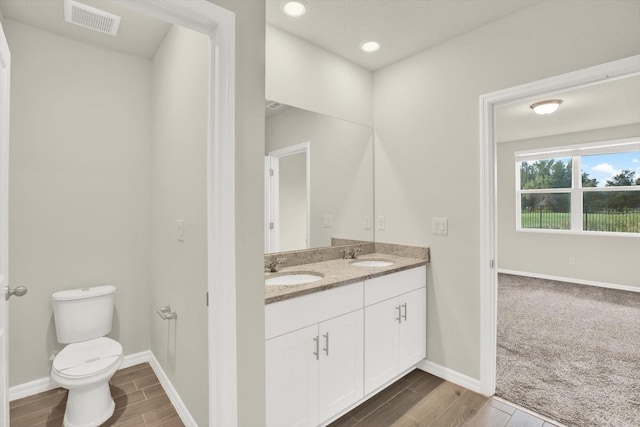 3146 Forrest Plum Ct, Zephyrhills, FL 33540 - full bath with double vanity, toilet, wood finished floors, baseboards, and recessed lighting