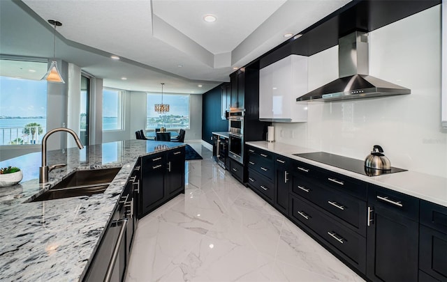 1 Seaside Ln Unit 302, Belleair, FL 33756 - kitchen featuring wall chimney range hood, dark cabinets, black electric stovetop, hanging light fixtures, and recessed lighting