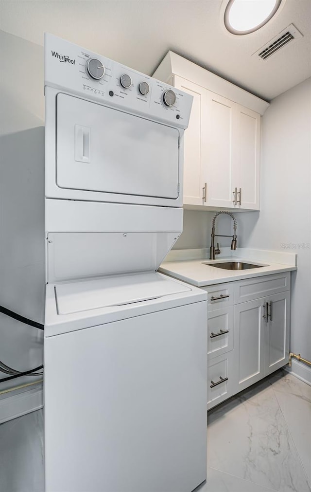 1 Seaside Ln Unit 302, Belleair, FL 33756 - laundry room with estacked washer and dryer, light marble finish floors, and cabinet space