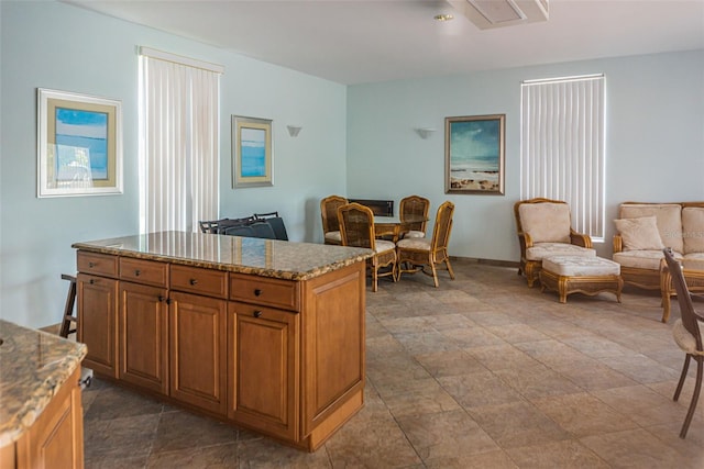1 Seaside Ln Unit 302, Belleair, FL 33756 - kitchen with open floor plan, brown cabinetry, light stone counters, and a kitchen island