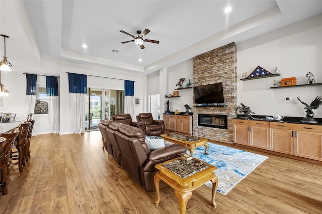 33219 Kateland Dr, Wesley Chapel, FL 33545 - living room with a raised ceiling, ceiling fan, light wood finished floors, recessed lighting, and a stone fireplace