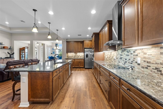 33219 Kateland Dr, Wesley Chapel, FL 33545 - kitchen with wall chimney range hood, stainless steel appliances, a kitchen bar, a sink, and hardwood / wood-style flooring