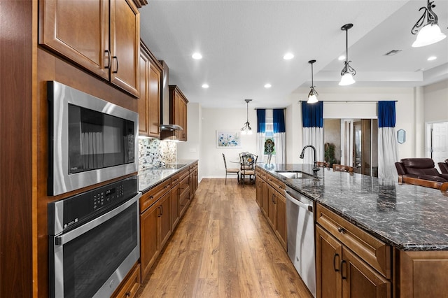 33219 Kateland Dr, Wesley Chapel, FL 33545 - kitchen with a sink, appliances with stainless steel finishes, wood finished floors, a large island with sink, and backsplash